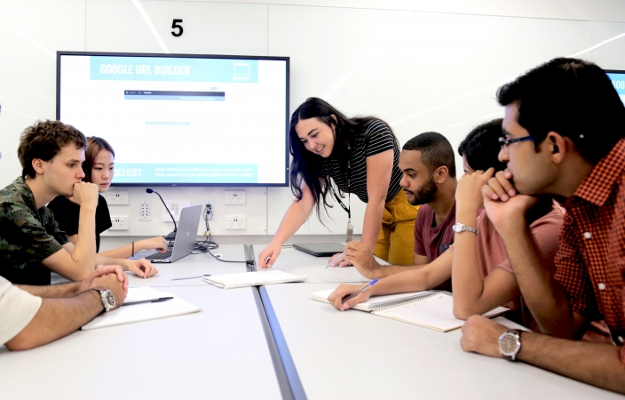 UNSW students hovering around a meeting table discussing initiatives